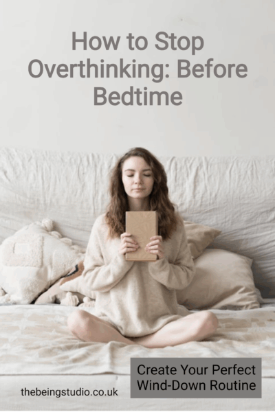 This pin offers advice on how to stop overthinking before bedtime. It suggests creating a perfect wind-down routine for better sleep hygiene. The image shows a woman sitting cross-legged on a bed, holding a book and appearing calm. This visual relates to mental wellness, self-care practices, and achieving a peaceful state for sleep. It could be useful for anyone struggling with anxiety or racing thoughts at night. The website thebeingstudio.co.uk is also featured, likely offering more resources on these topics.